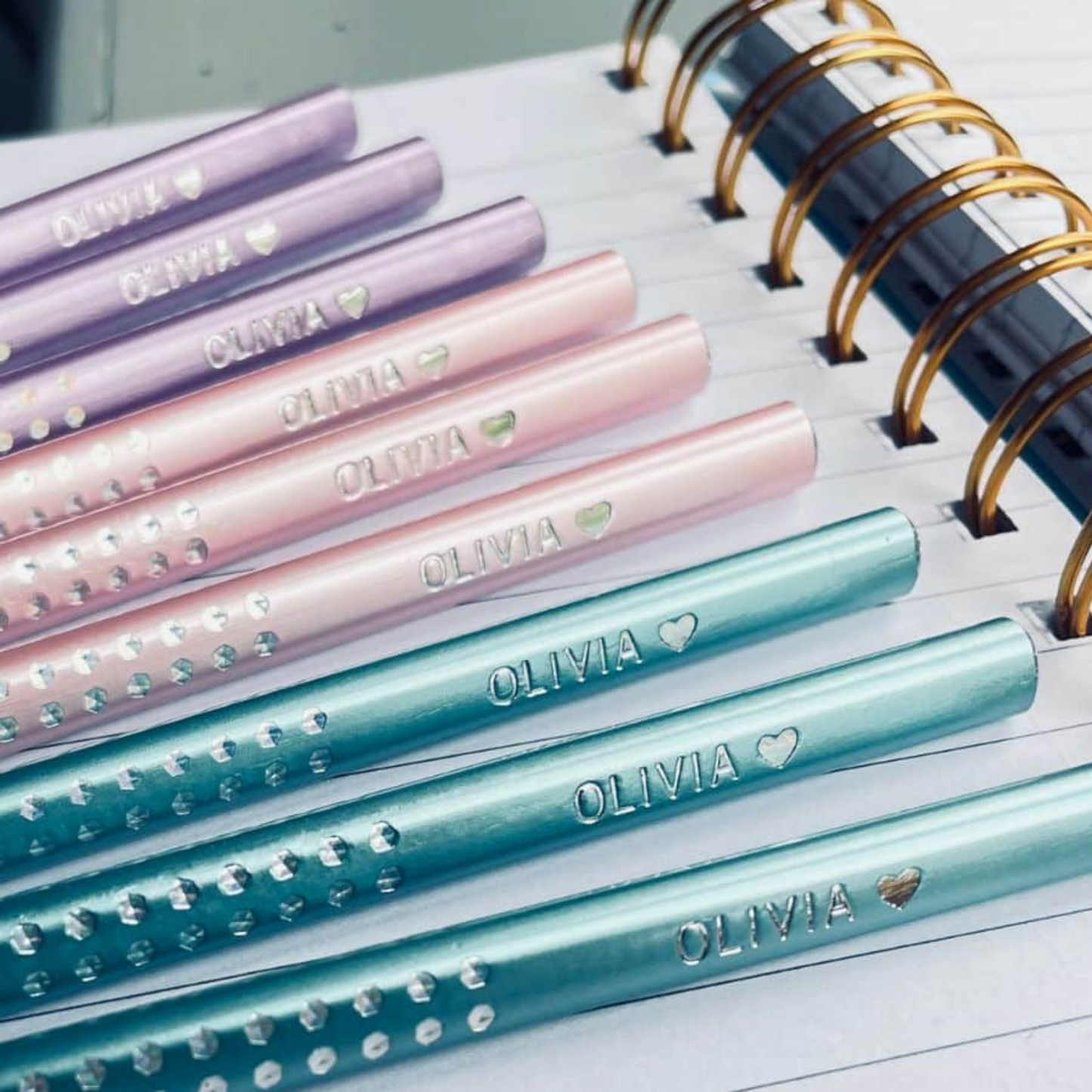 Elegant set of Faber-Castell Sparkle pencils personalized for students, displayed against a backdrop of school notebooks.